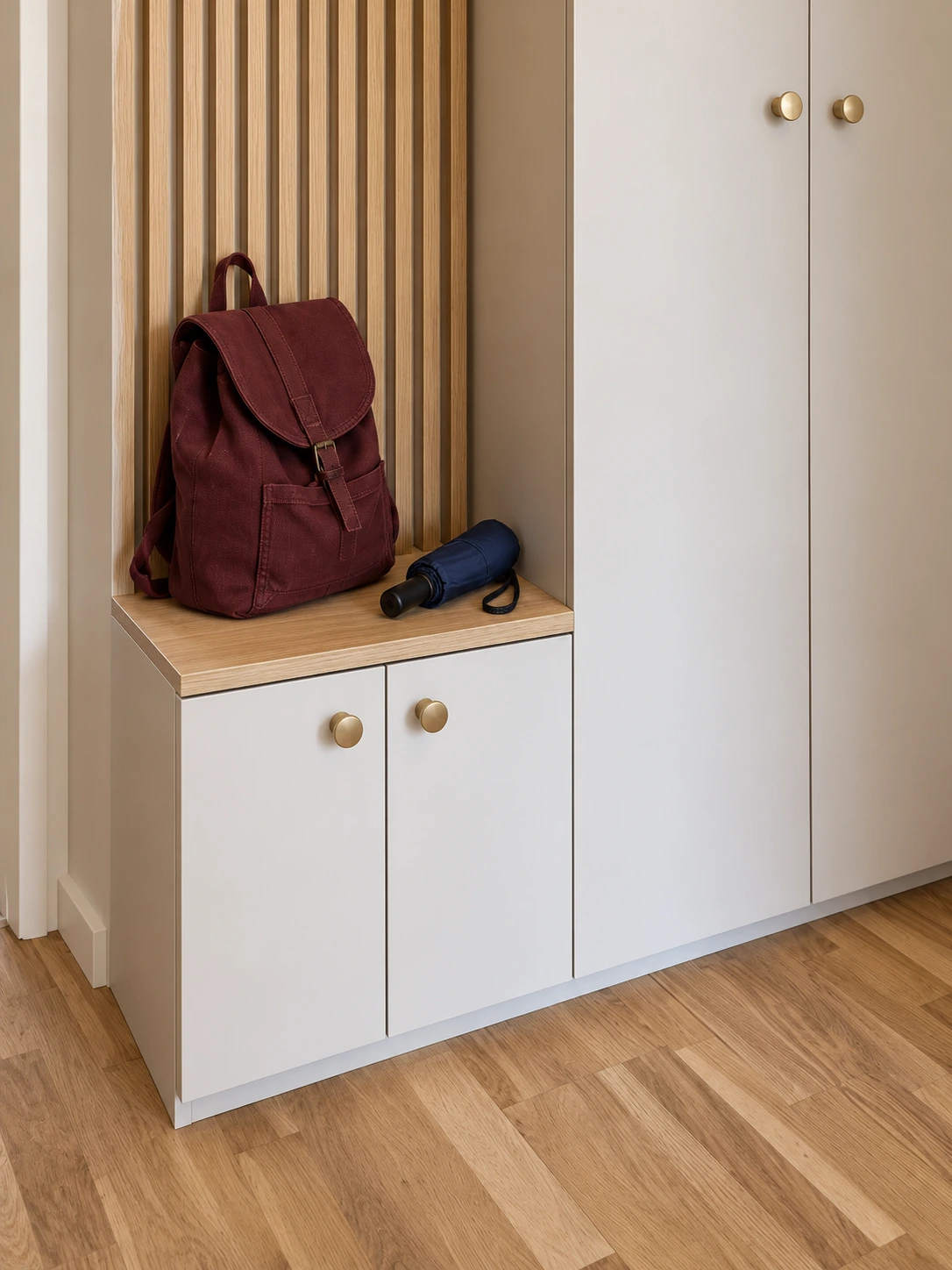 Banquette en décor bois avec sac à dos et parapluie, deux portes basses fermées