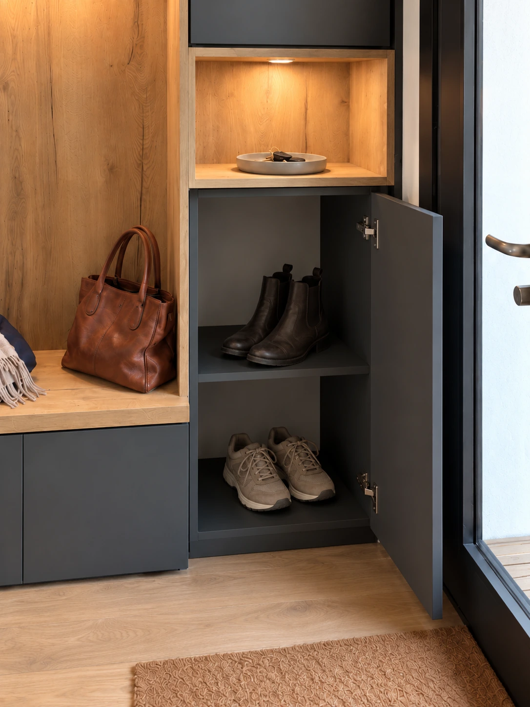 Rangement à chaussures ouvert sous la niche éclairée, près de la porte d’entrée