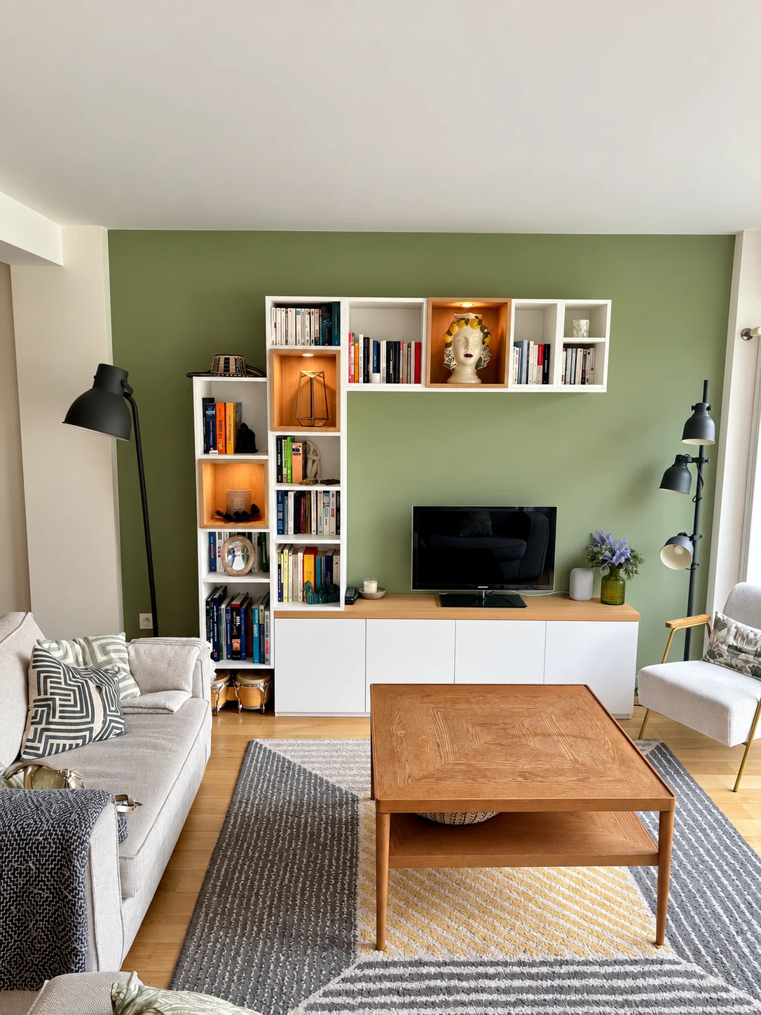 Bibliothèque et meuble TV blanc et bois sur un mur vert, avec niches éclairées