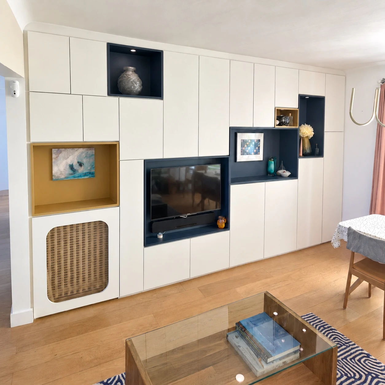 Meuble de salon blanc à niches bleu profond et ocre, télévision et cache-radiateur à Versailles
